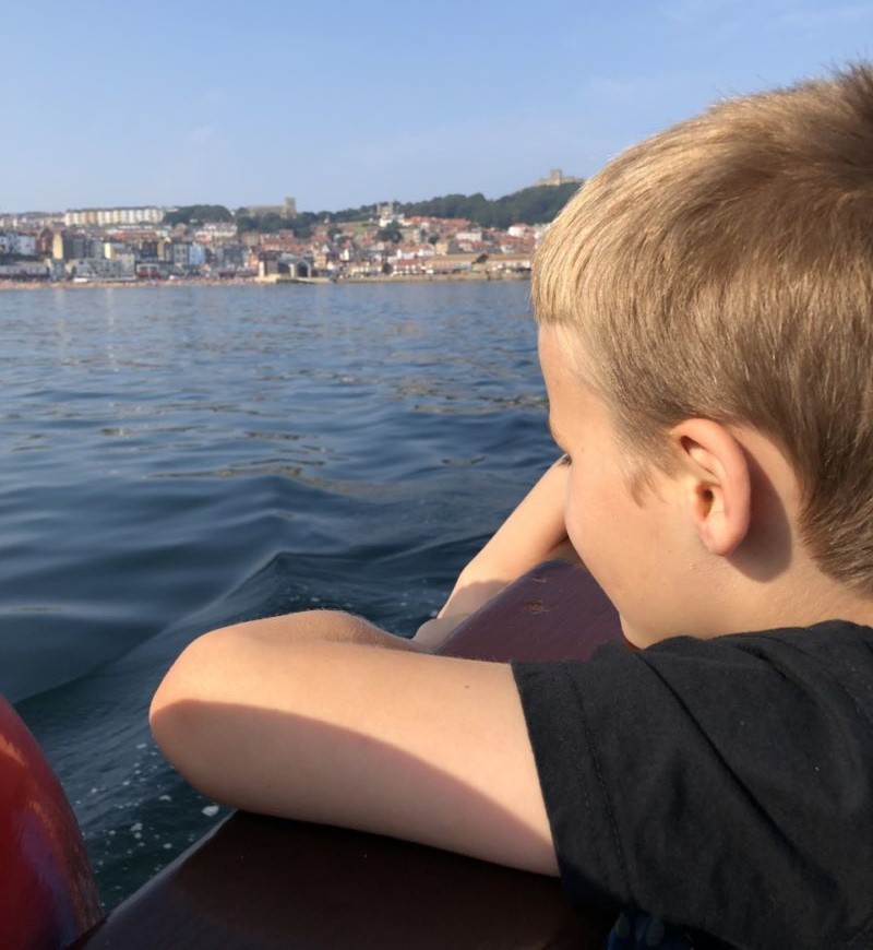 A boy looking out to sea on a boat trip.