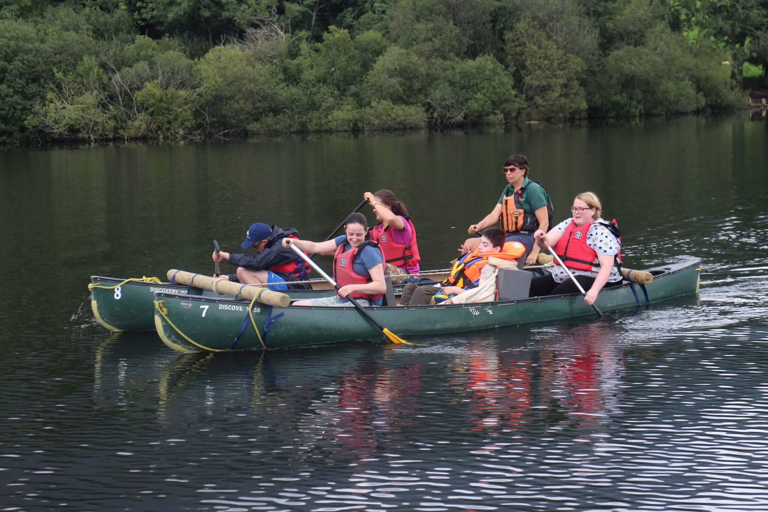 A group of holiday guests canoeing in the Lake District.
